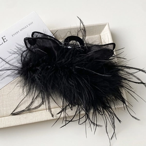 Detail of elegant black feather and tulle fabric hair claw clip on aesthetic tray