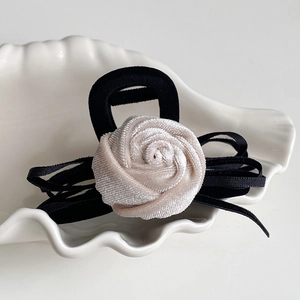 Detail of elegant velvet rose hair claw clip with black ribbon bow in a shell dish