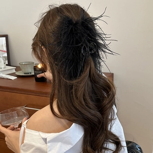 Detailed view of elegant black feather hair claw clip for voluminous hair styling