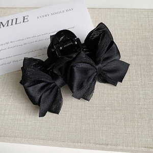 Détail de la pince à cheveux double nœud papillon noir avec une texture finement pailletée