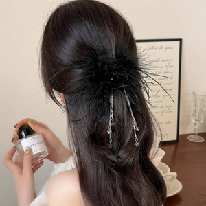 Détail de la pince à cheveux en plumes noires avec chaînes argentées et perles sur l'arrière