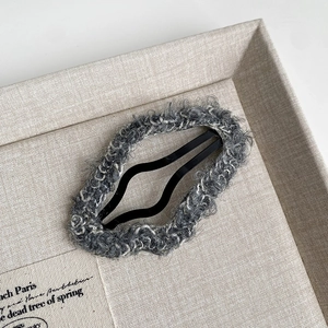 Close-up of soft plush dark grey hair clip with cozy fuzzy texture on fabric tray
