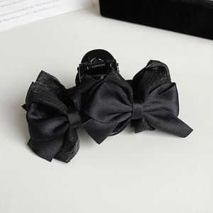 Détail d'une pince à cheveux noire avec nœud en tulle et paillettes discrètes
