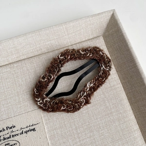 Close-up of coffee brown plush hair clip with soft knitted texture and metal wave clip