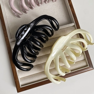 Detailed macro view of large octopus hair claws in cream, pink, and black finishes