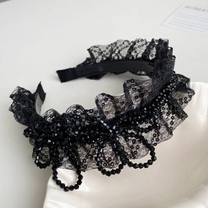 Détail d'un serre-tête en dentelle noire élégante avec des perles et finitions raffinées