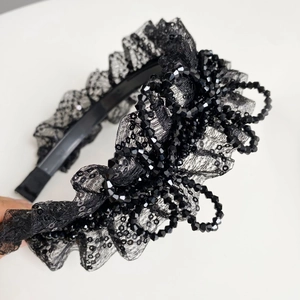 Gros plan sur un serre-tête en dentelle noire avec perles et texture plissée rétro