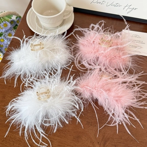 Détail de grandes pinces à cheveux en plumes blanches et roses sur une table en bois