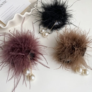 Détail de pinces à cheveux en plumes avec pompons de perles en noir, rouge et marron