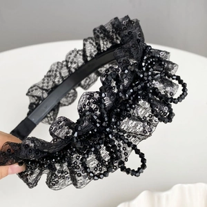 Vue détaillée du serre-tête en dentelle noire plissée avec des paillettes et perles foncées