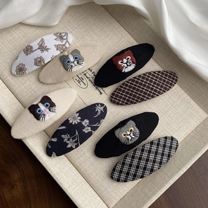 Détail de huit barrettes en tissu avec des motifs de chats brodés et des fleurs