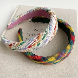 Detailed close-up of woven cotton and colorful plaid sponge headbands on a linen book