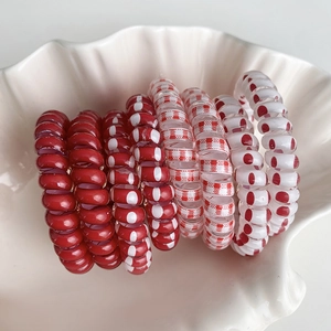 Lot de sept élastiques spirale rouges et blancs avec pois et carreaux dans un plateau coquille