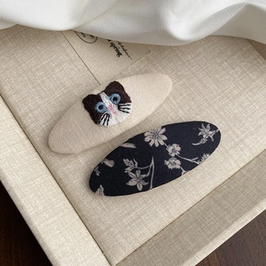 Détail de barrettes en tissu avec broderie de chat mignon et motifs floraux vintage