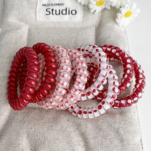 Détail d'élastiques à cheveux spirale à pois rouges et blancs sur fond de lin rustique