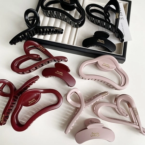 Detail shot of matte heart and cross-shaped claw clips in black, wine red, and pink colors