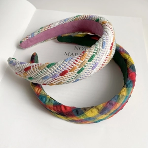 Detailed macro of a thick braided rainbow headband and a classic plaid sponge hairband
