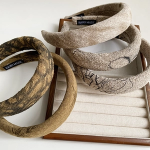 Detailed close-up of retro floral sponge headbands in wood tray with handmade labels