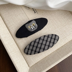 Détail de deux pinces à cheveux avec broderie chat noir mignonne et motif à carreaux