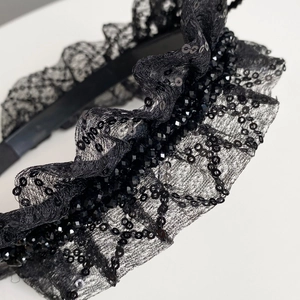Gros plan du serre-tête en dentelle noire avec paillettes et perles facettées brillantes