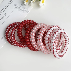 Détail d'élastiques à cheveux spirale rouges à pois et carreaux sur fond de fleurs