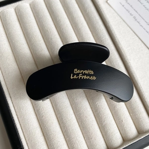 Close-up of matte black hair claw clip with gold Barrette La France lettering in jewelry box
