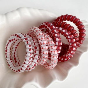 Élastiques spirales à pois rouges et blancs dans un plateau coquille pour queue de cheval
