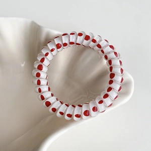 Vue détaillée d'un élastique spirale à pois rouges sur un plateau en forme de coquillage