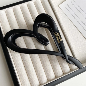 Detailed macro view of matte black heart-shaped hair claw with gold Barrette lettering