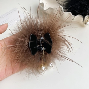 Détail d'une pince à cheveux en plumes marron avec perles blanches et chaînes dorées
