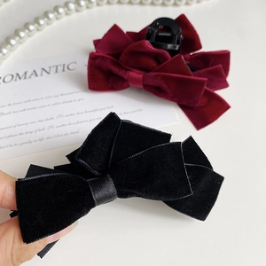 Detailed view of elegant velvet double bow hair claws in classic black and burgundy red