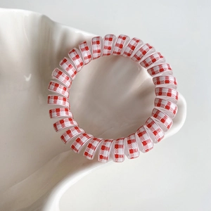 Gros plan d'un élastique spirale à damier rouge et blanc dans un plat en coquillage
