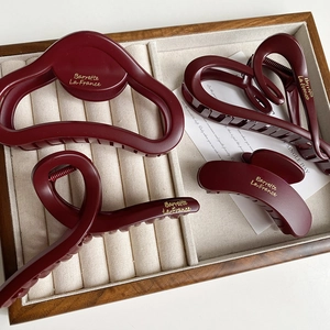 Set of four matte burgundy hair claws with gold Barrette La France text on velvet tray