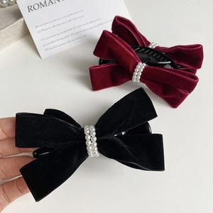 Close-up of elegant velvet bow hair clips in black and burgundy with pearl accents