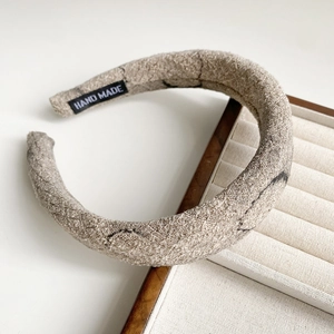 Detailed close-up of beige ink print fabric headband with a woven HAND MADE label inside