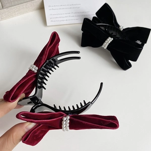Macro detail of velvet bow hair claw clip with elegant imitation pearl embellishments