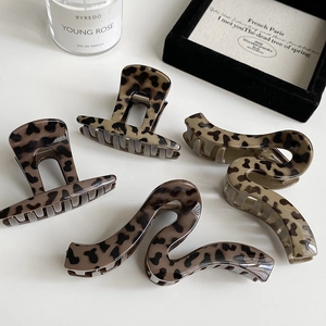Set of four leopard print hair claws in square and wavy styles on a minimalist background