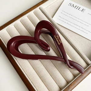 Detail of burgundy matte heart hair claw clip with golden lettering on jewelry tray