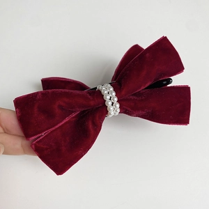 Detail of elegant wine red velvet bow hair clip with white pearl center embellishments