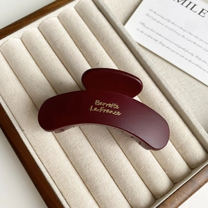 Close-up of matte wine red hair claw clip with golden Barrette La France lettering