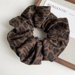 Close-up of leopard print fabric scrunchie with soft twill texture and elastic design