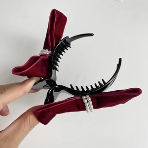 Detail of dark red velvet bow hair claw clip with white pearls and sturdy black teeth