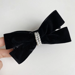 Close-up of elegant black velvet bow hair clip with luxury white faux pearl rows
