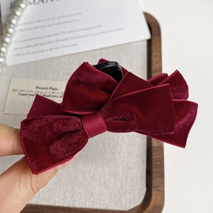 Detail of burgundy velvet layered bow hair claw clip on vintage aesthetic background