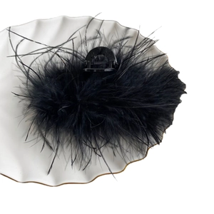 Elegant large black feather hair claw clip on a minimalist white ceramic jewelry tray