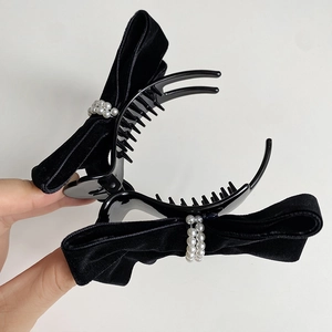 Detail of elegant black velvet bow hair claw clip with a decorative faux pearl accent