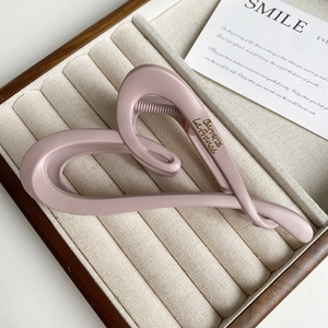 Detail view of pink matte heart hair claw clip with gold French lettering on side