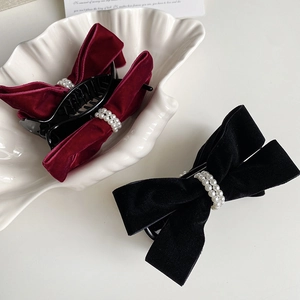 Close-up of elegant velvet bow hair claws with pearl accents in black and burgundy