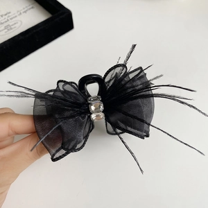Detail of black bow hair claw with feathers, mesh, and crystals in a retro French style