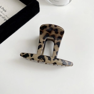 Macro detail of high-shine tortoiseshell hair claw clip with vintage leopard print